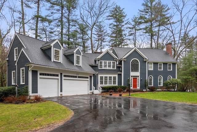 view of front facade featuring a garage, a front lawn, a chimney, a shingled roof, and driveway