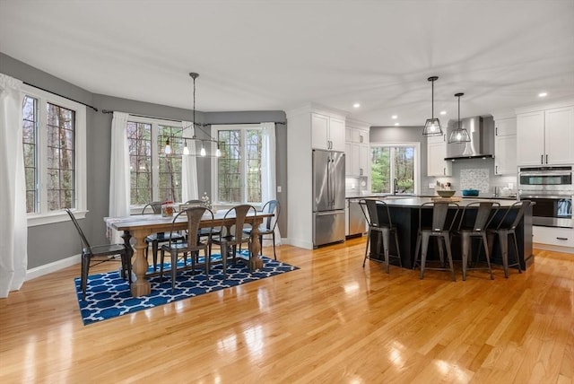 dining area with light wood-style flooring, baseboards, a notable chandelier, and recessed lighting