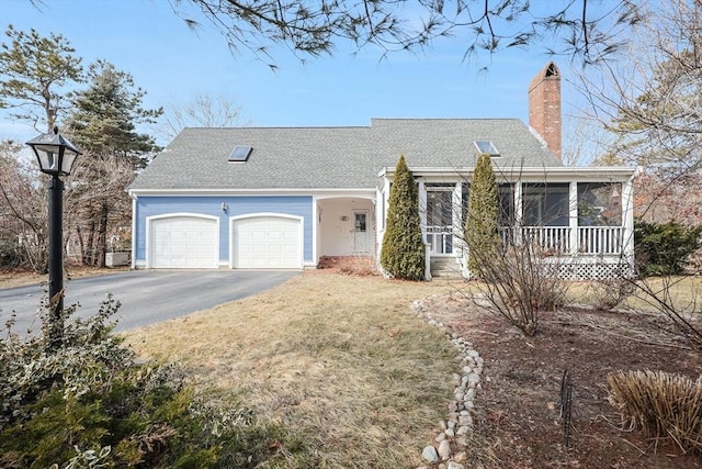 view of front facade featuring an attached garage, a shingled roof, a front lawn, a chimney, and driveway