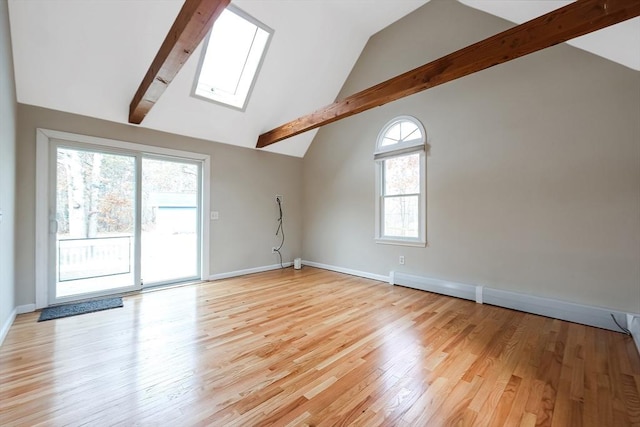 empty room with vaulted ceiling with skylight, light wood-style flooring, and baseboards