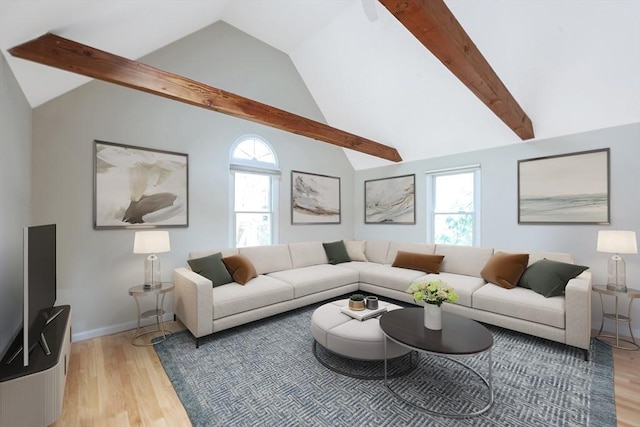 living area with lofted ceiling with beams, light wood-style flooring, and a healthy amount of sunlight