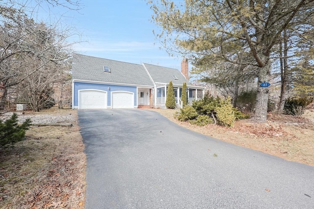 view of front of home with a garage, a chimney, and driveway