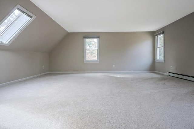 additional living space featuring a wealth of natural light, light colored carpet, lofted ceiling with skylight, and baseboards