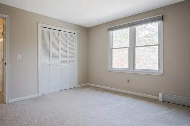 unfurnished bedroom with a closet, light carpet, and baseboards