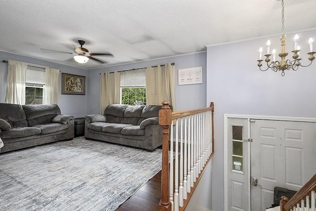 living room with a chandelier, ornamental molding, a textured ceiling, wood finished floors, and a ceiling fan