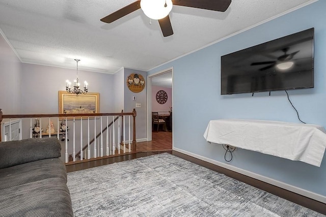 living room with crown molding, a ceiling fan, a chandelier, wood finished floors, and a textured ceiling