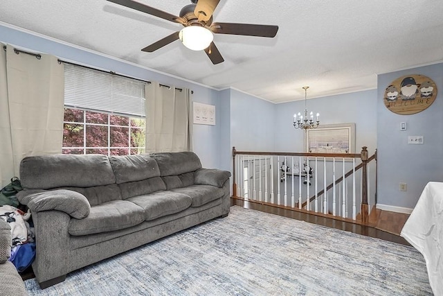 living room with a chandelier, a ceiling fan, wood finished floors, ornamental molding, and a textured ceiling