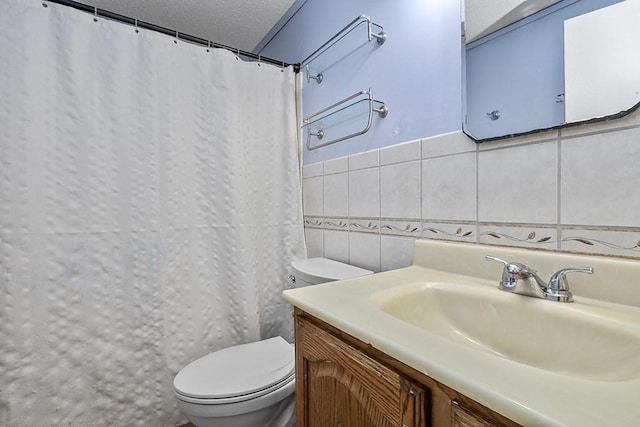 full bath with tile walls, toilet, vanity, a shower with curtain, and a textured ceiling