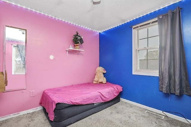 carpeted bedroom featuring multiple windows, a textured ceiling, and baseboards