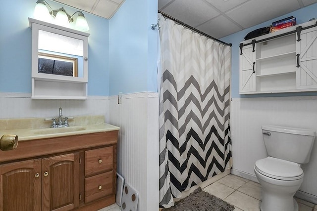 full bathroom featuring toilet, a wainscoted wall, tile patterned flooring, vanity, and a shower with curtain
