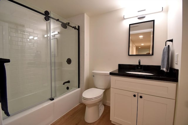 full bathroom with enclosed tub / shower combo, vanity, toilet, and wood finished floors