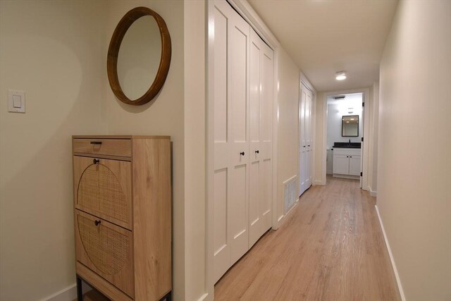 corridor featuring light wood-style floors and baseboards