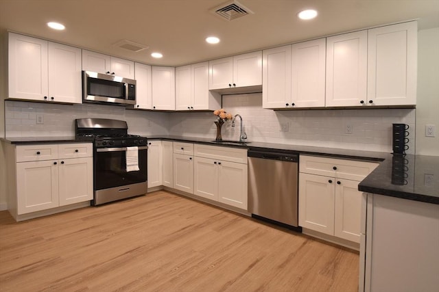 kitchen with appliances with stainless steel finishes, dark countertops, and white cabinets