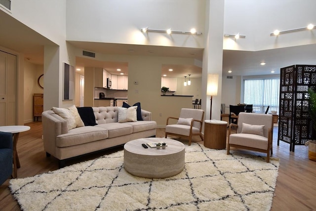 living area with a towering ceiling, wood finished floors, and visible vents