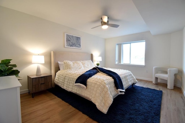 bedroom with light wood-style floors, ceiling fan, and baseboards