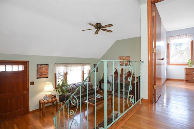 corridor featuring baseboards, wood finished floors, stairs, and vaulted ceiling