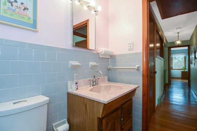 bathroom with toilet, tile walls, wainscoting, and vanity