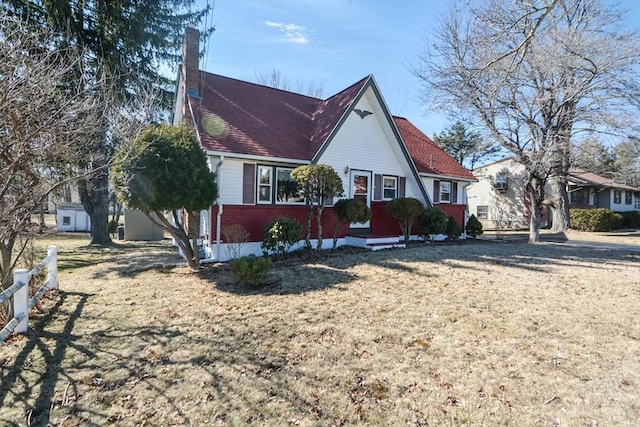 view of front facade with fence, brick siding, and a chimney