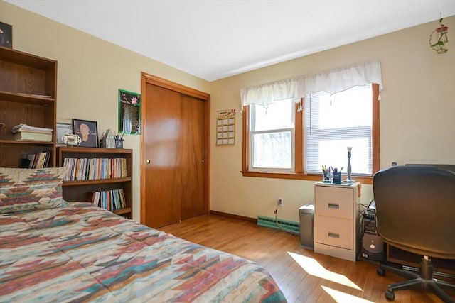 bedroom featuring baseboards, a closet, wood-type flooring, and a baseboard radiator