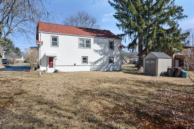 back of house featuring a yard, a storage unit, and an outdoor structure