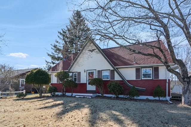 view of front of property featuring brick siding, roof with shingles, and a chimney