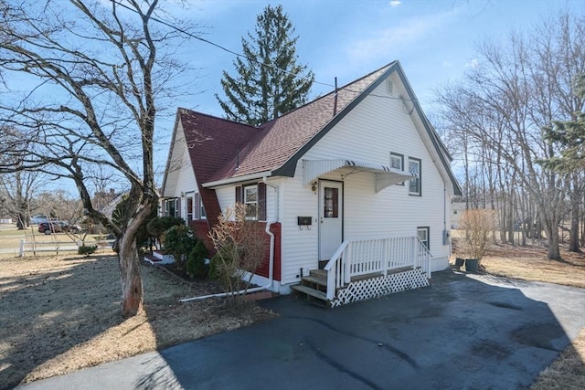 view of front of house with roof with shingles and driveway