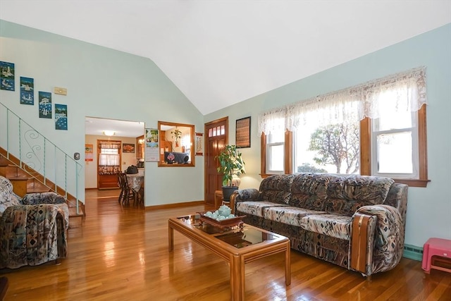 living area featuring a healthy amount of sunlight, wood finished floors, and stairs