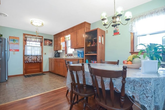 dining space with light tile patterned floors, a notable chandelier, and baseboards