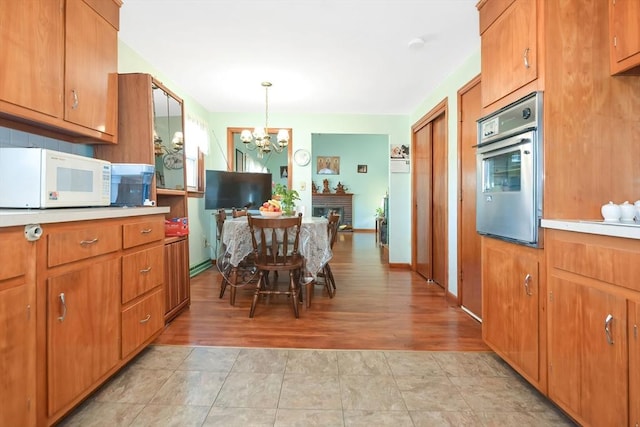 kitchen with light countertops, white microwave, brown cabinets, and oven