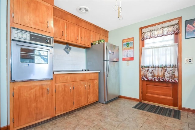 kitchen featuring oven, visible vents, tasteful backsplash, freestanding refrigerator, and light countertops