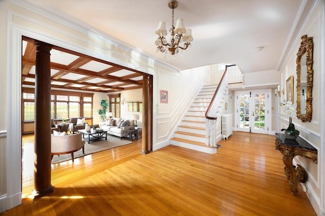 foyer entrance featuring light hardwood / wood-style flooring, ornamental molding, and a chandelier