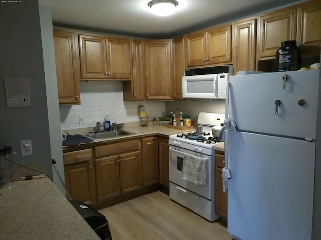 kitchen with white appliances, sink, decorative backsplash, and light wood-type flooring