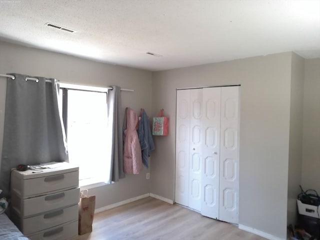 bedroom featuring a textured ceiling, light wood-type flooring, and a closet