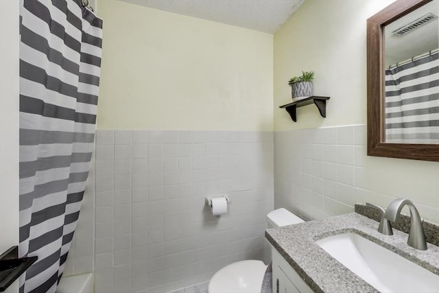 bathroom featuring tile walls, vanity, a textured ceiling, curtained shower, and toilet