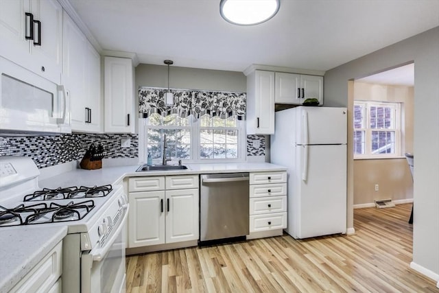 kitchen with sink, decorative light fixtures, white appliances, decorative backsplash, and white cabinets