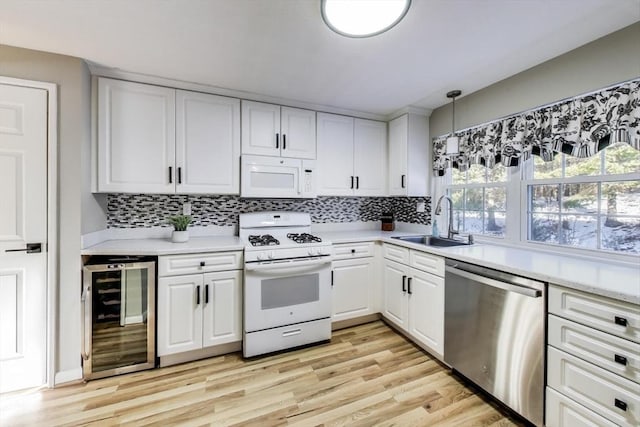 kitchen with sink, white cabinetry, hanging light fixtures, white appliances, and beverage cooler