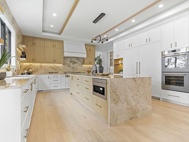 kitchen featuring premium range hood, white cabinetry, a large island, decorative light fixtures, and stainless steel appliances