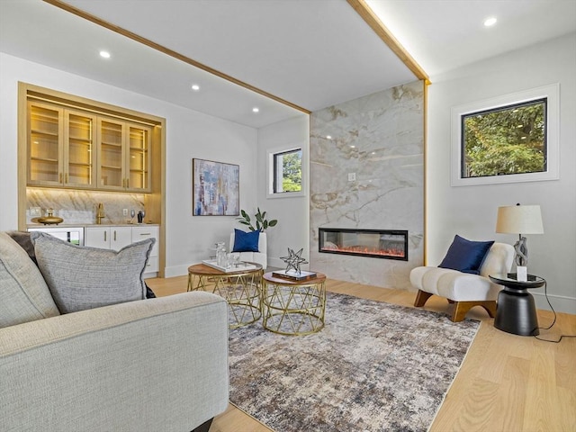 living room with a tile fireplace and light wood-type flooring