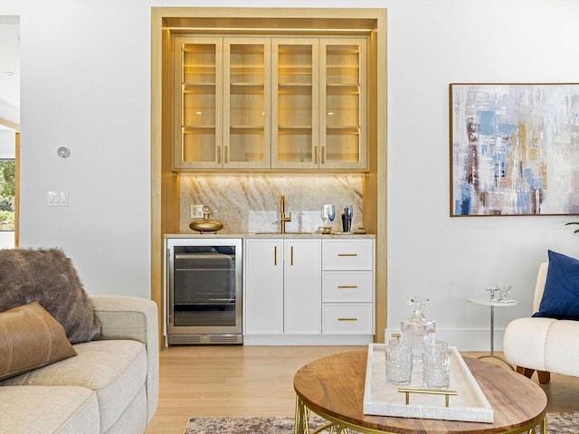 bar featuring white cabinetry, sink, light hardwood / wood-style flooring, backsplash, and wine cooler