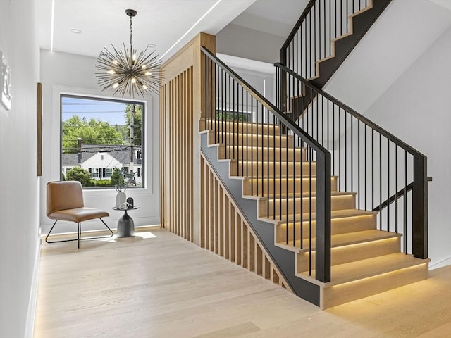 stairway with hardwood / wood-style floors and a notable chandelier