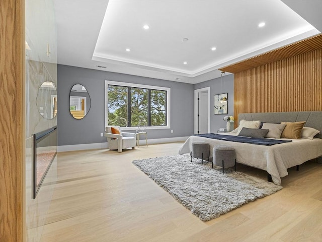 bedroom featuring a raised ceiling and light hardwood / wood-style flooring