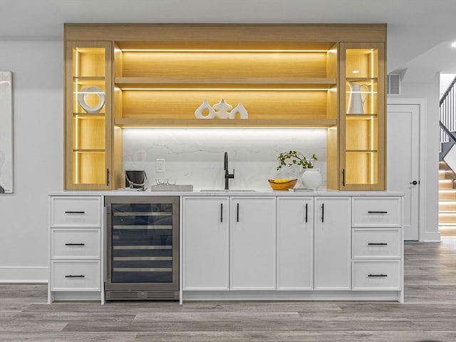 bar with sink, hardwood / wood-style floors, white cabinetry, and wine cooler