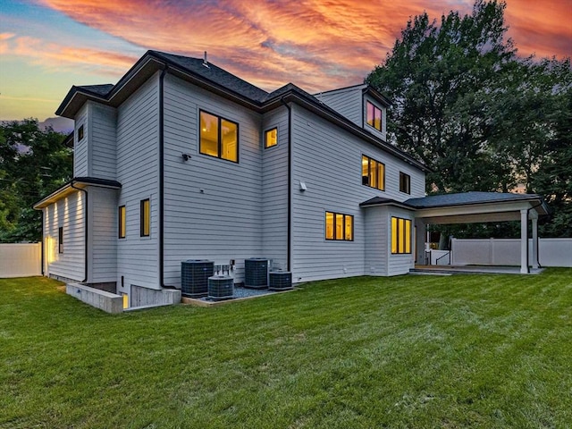 back house at dusk featuring a patio and a yard