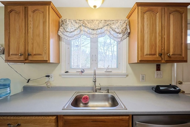 kitchen with a sink, brown cabinets, dishwasher, and light countertops