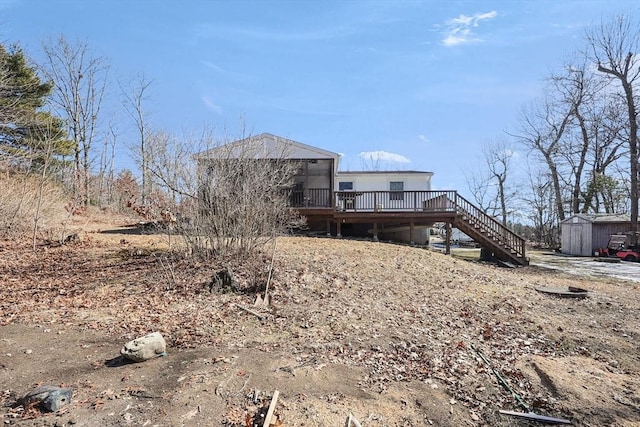 rear view of property featuring a wooden deck, an outbuilding, stairs, and a shed