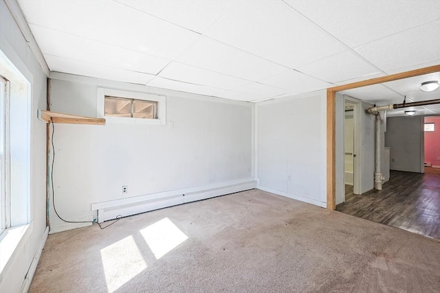 basement featuring a baseboard heating unit and carpet