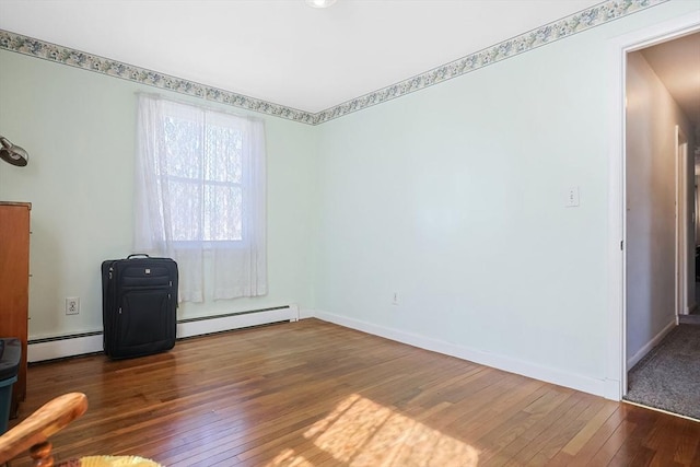 empty room featuring baseboards, baseboard heating, and hardwood / wood-style flooring