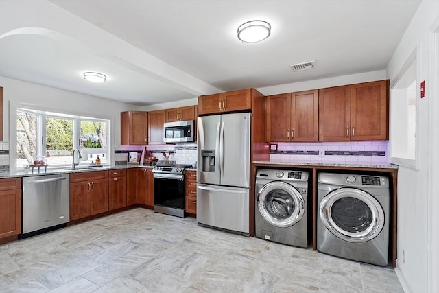 clothes washing area with visible vents, a sink, washer and dryer, and laundry area