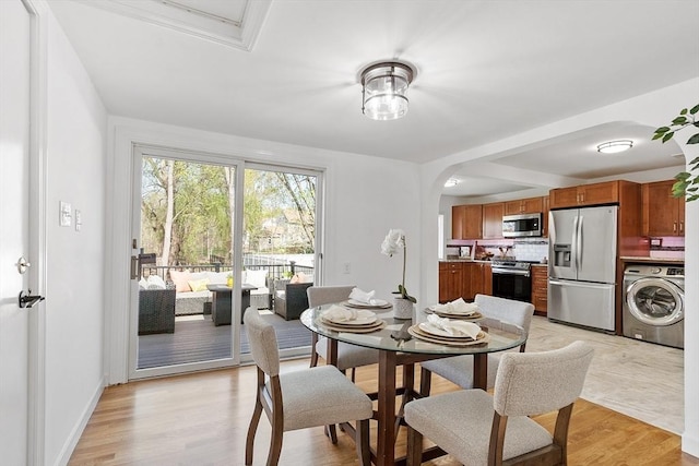 dining area featuring light wood-type flooring, arched walkways, and washer / dryer
