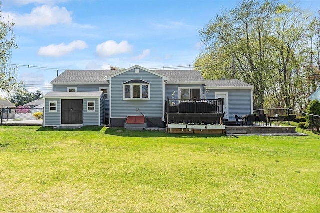 rear view of property featuring a lawn, a shingled roof, and a deck